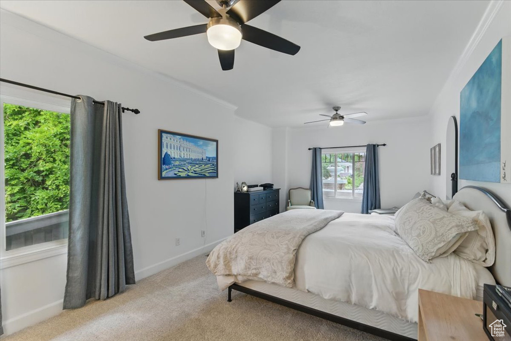 Bedroom featuring light colored carpet, baseboards, a ceiling fan, and ornamental molding
