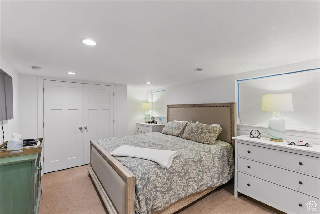 Bedroom with light colored carpet, recessed lighting, and a closet