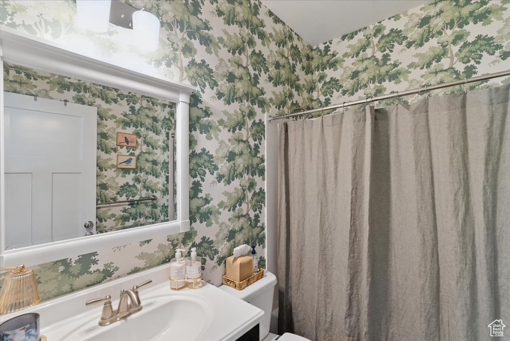 Bathroom with wallpapered walls, toilet, and vanity