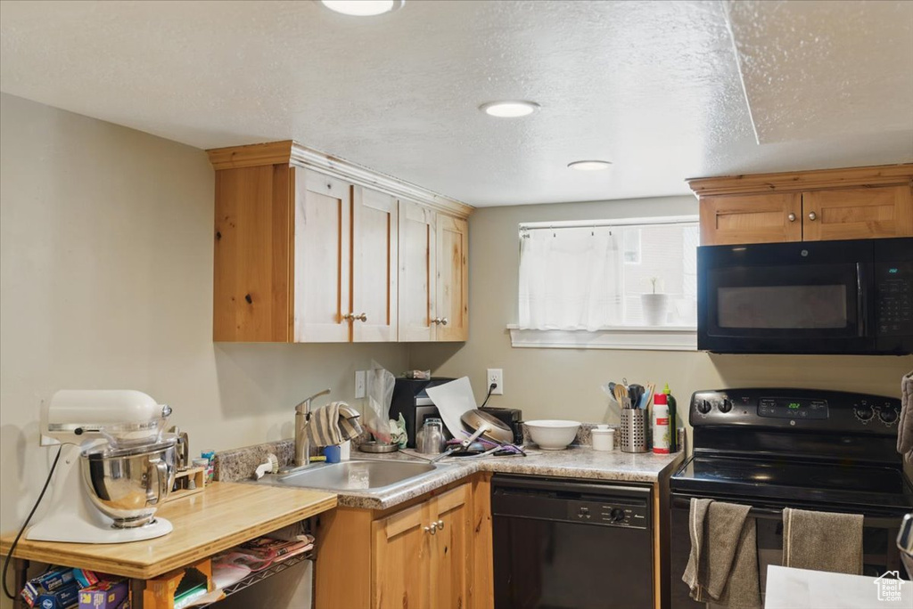 Kitchen with black appliances, a sink, and light countertops