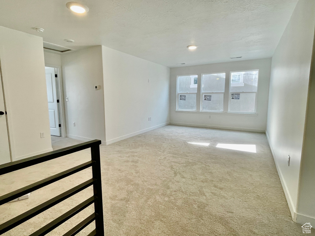 Spare room featuring light carpet, a smoke detector, a textured ceiling, and recessed lighting