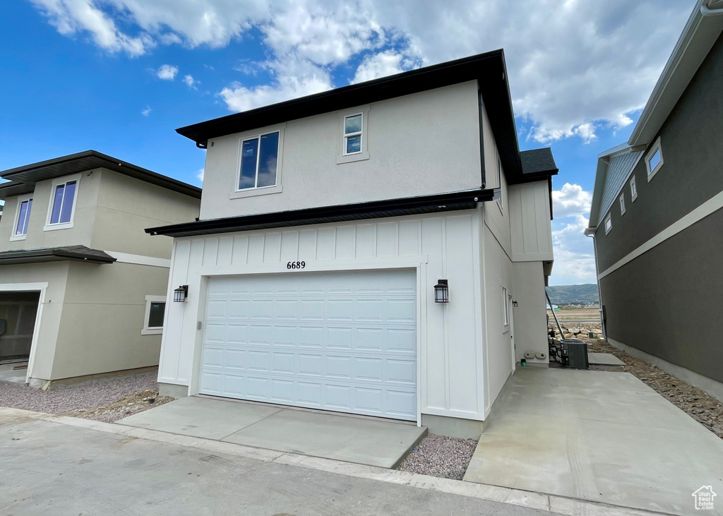 View of property exterior with a garage, concrete driveway, and board and batten siding