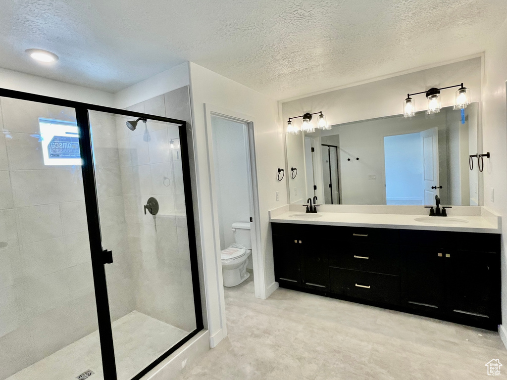 Full bath featuring a shower stall, double vanity, and a textured ceiling
