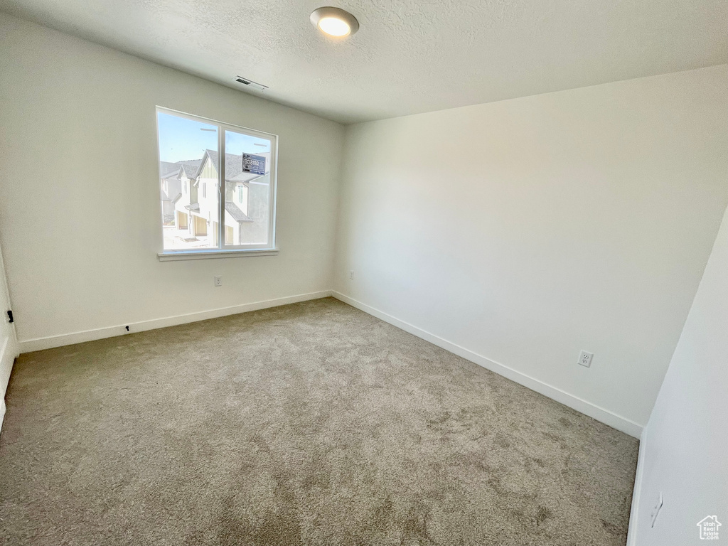 Carpeted empty room featuring baseboards and a textured ceiling