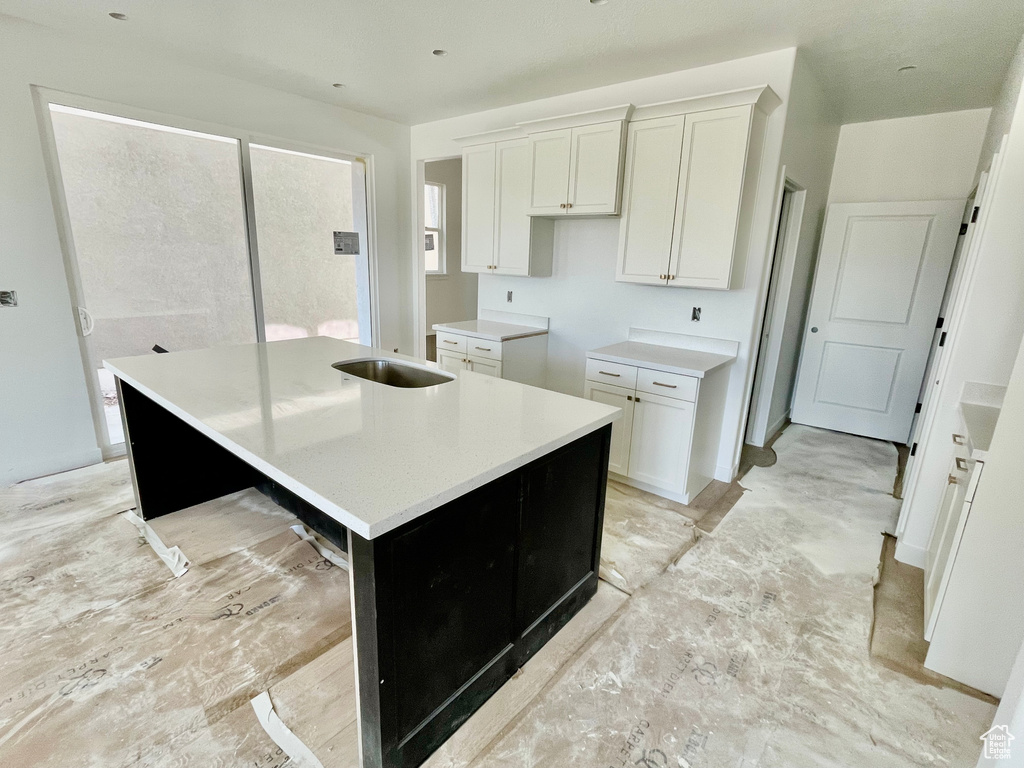 Kitchen with an island with sink and white cabinetry
