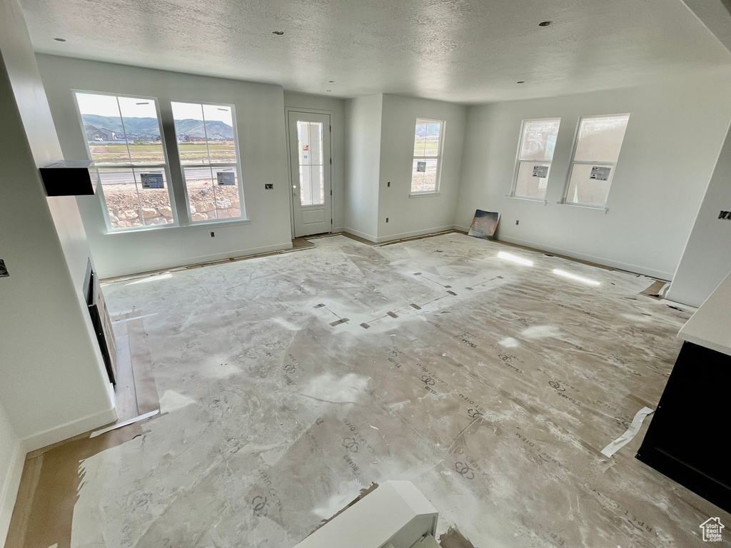 Unfurnished living room featuring a textured ceiling and baseboards