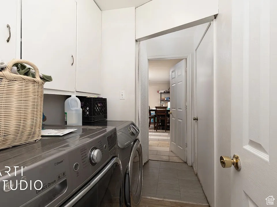 Laundry area with cabinet space, washing machine and clothes dryer, and light tile patterned flooring