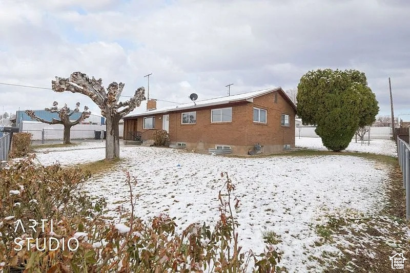 Snow covered house with a fenced backyard