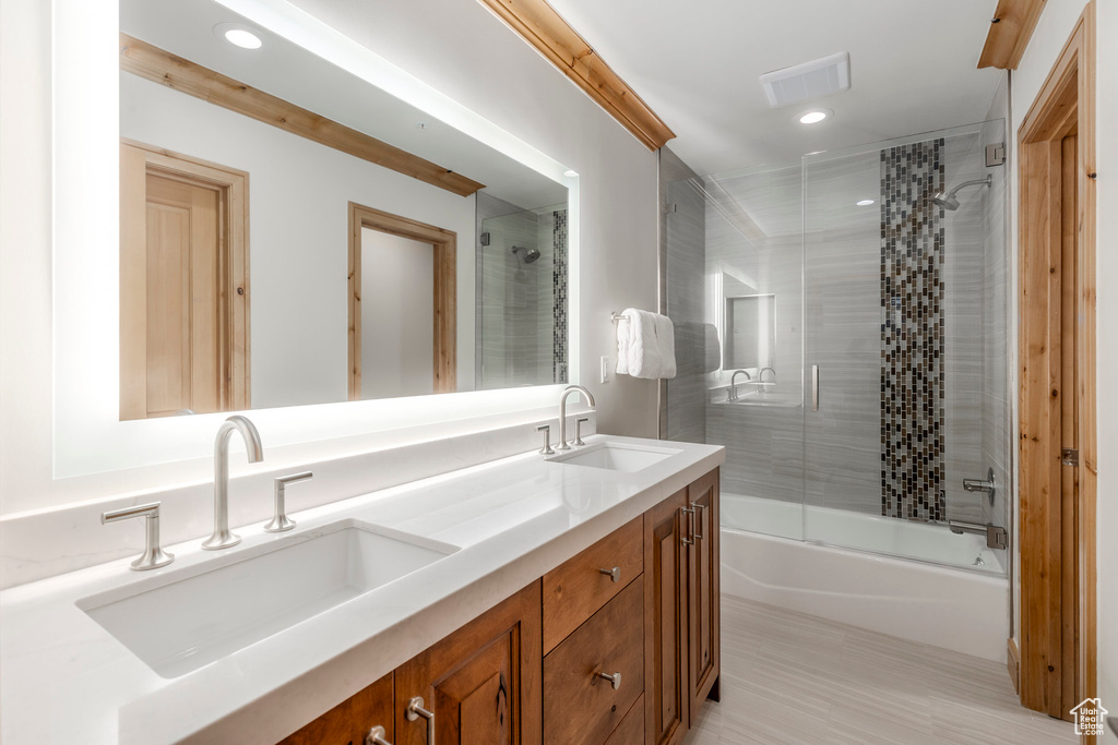 Bathroom featuring double vanity, shower / bath combination with glass door, and recessed lighting