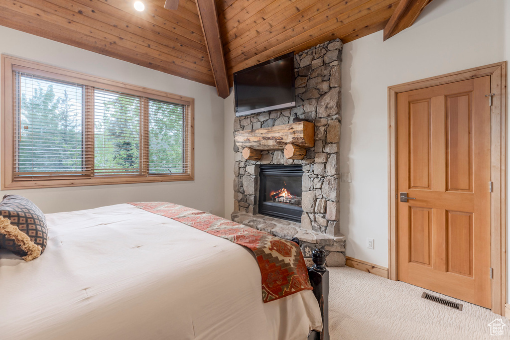 Bedroom with a stone fireplace, carpet, wooden ceiling with exposed beams, and baseboards