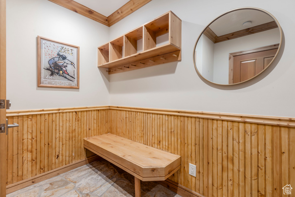Mudroom with a wainscoted wall, crown molding, and wooden walls