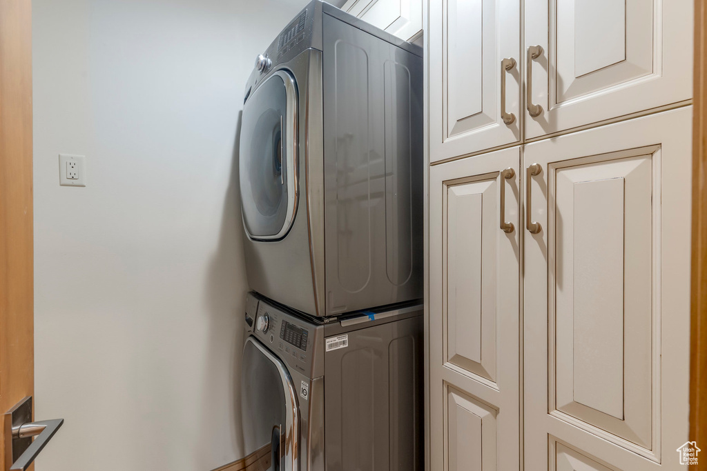 Washroom featuring cabinet space and stacked washer / dryer