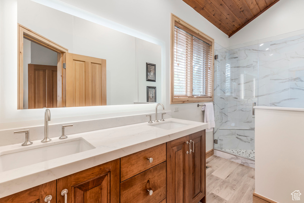 Full bathroom with a marble finish shower, double vanity, wooden ceiling, lofted ceiling, and wood finished floors