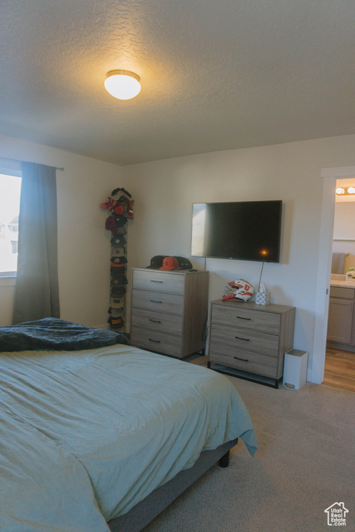 Bedroom with a textured ceiling, carpet floors, and connected bathroom