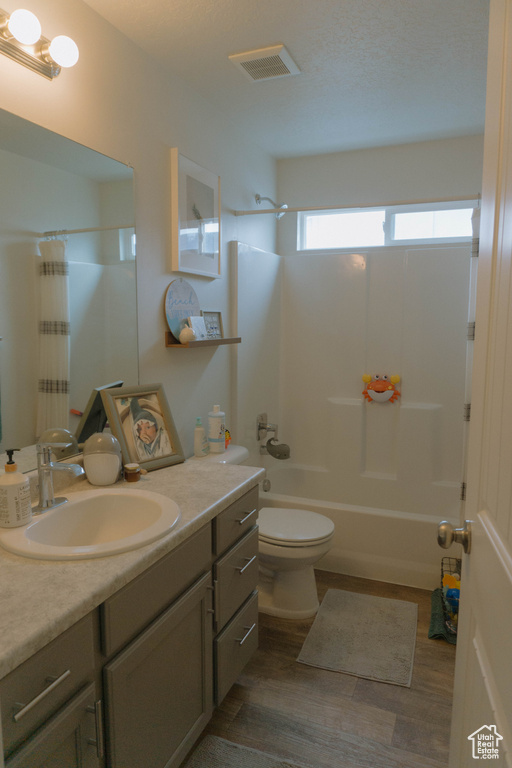 Bathroom with vanity, shower / tub combo, toilet, and wood finished floors