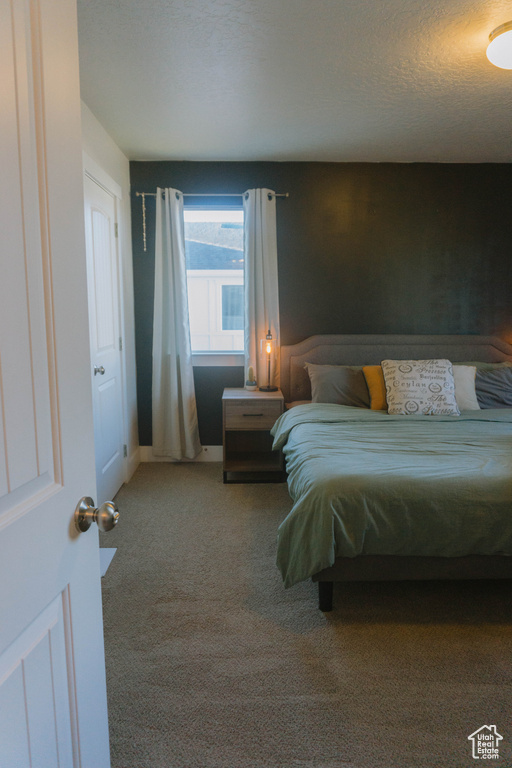 Carpeted bedroom with baseboards and a textured ceiling