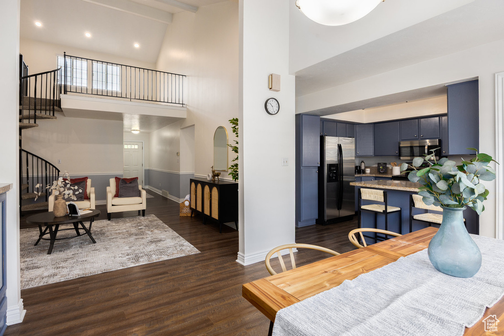 Dining room with high vaulted ceiling, stairway, dark wood-type flooring, baseboards, and arched walkways