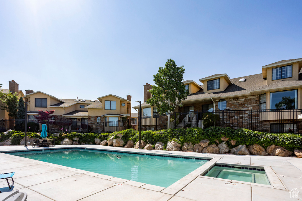 Community pool featuring a residential view, an in-ground hot tub, and a patio