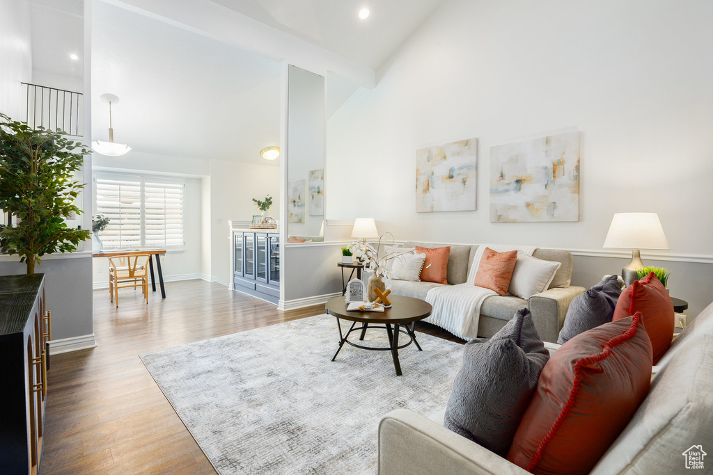 Living area featuring wood finished floors, high vaulted ceiling, baseboards, and recessed lighting