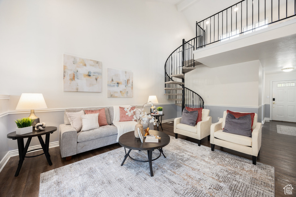Living room featuring wood finished floors, baseboards, stairs, and a towering ceiling