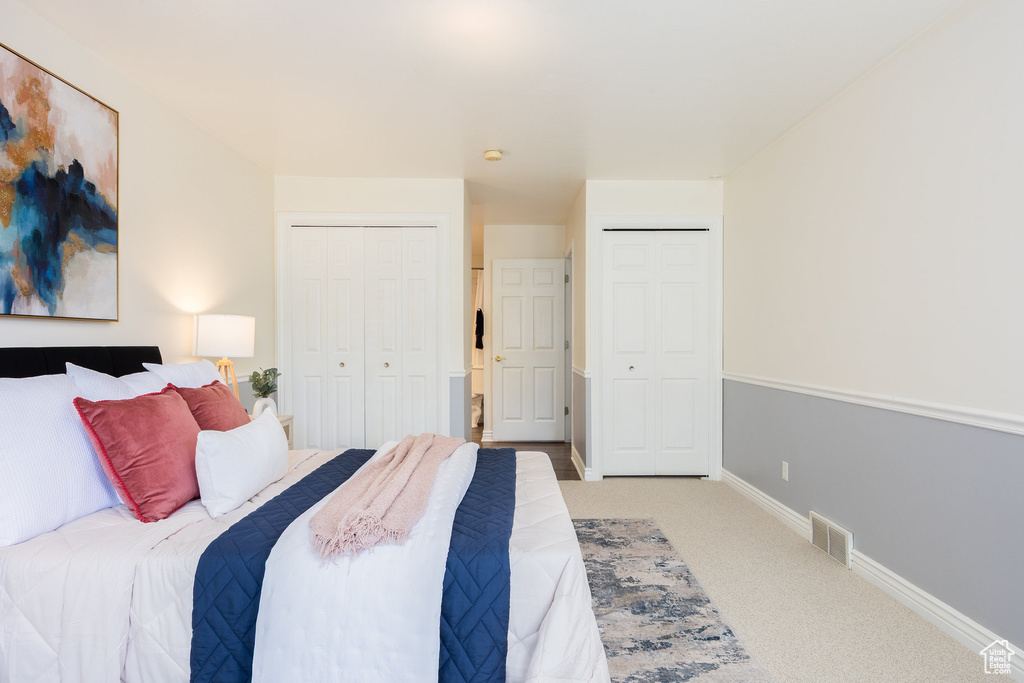 Carpeted bedroom with multiple closets and baseboards
