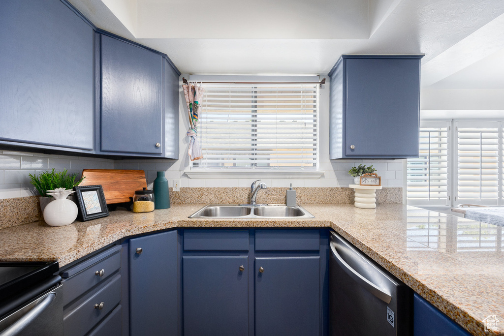 Kitchen featuring a sink, stainless steel dishwasher, blue cabinetry, and tasteful backsplash