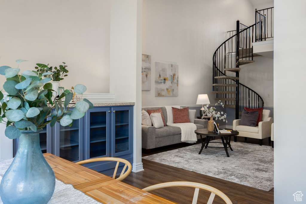 Living area featuring wood finished floors, a towering ceiling, and stairs