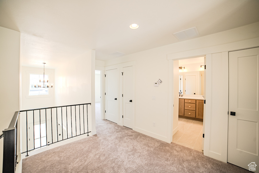 Hallway with a chandelier, light carpet, recessed lighting, and baseboards
