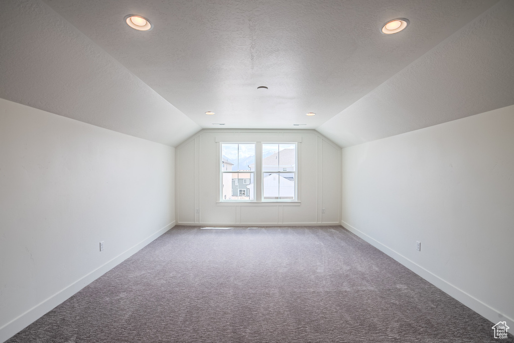 Additional living space with carpet floors, lofted ceiling, baseboards, a textured ceiling, and recessed lighting
