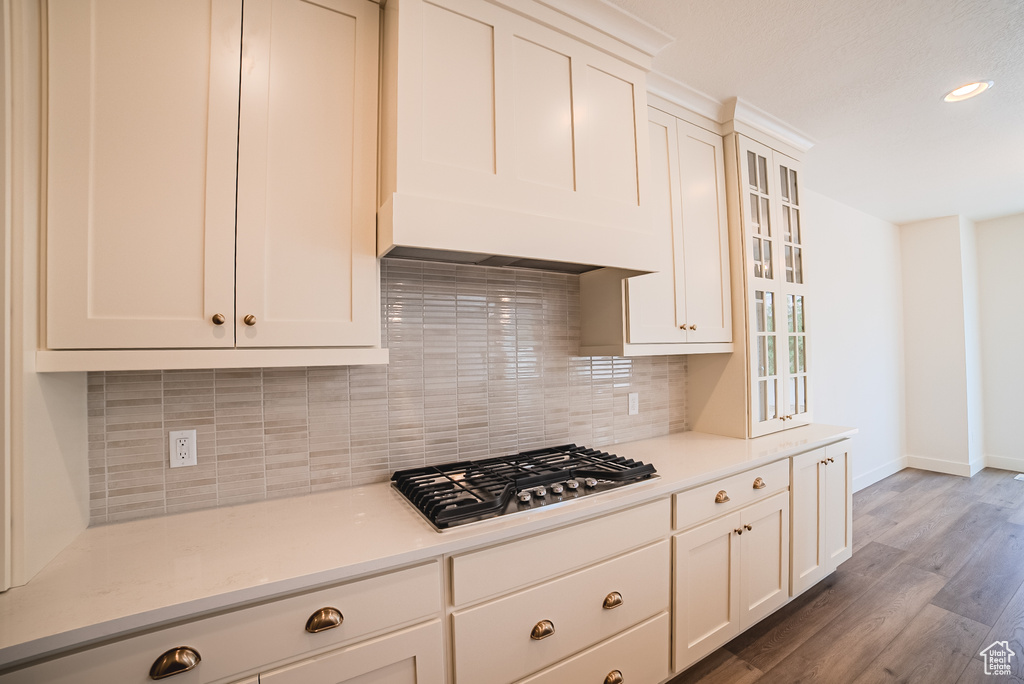 Kitchen with stainless steel gas cooktop, baseboards, wood finished floors, light countertops, and recessed lighting