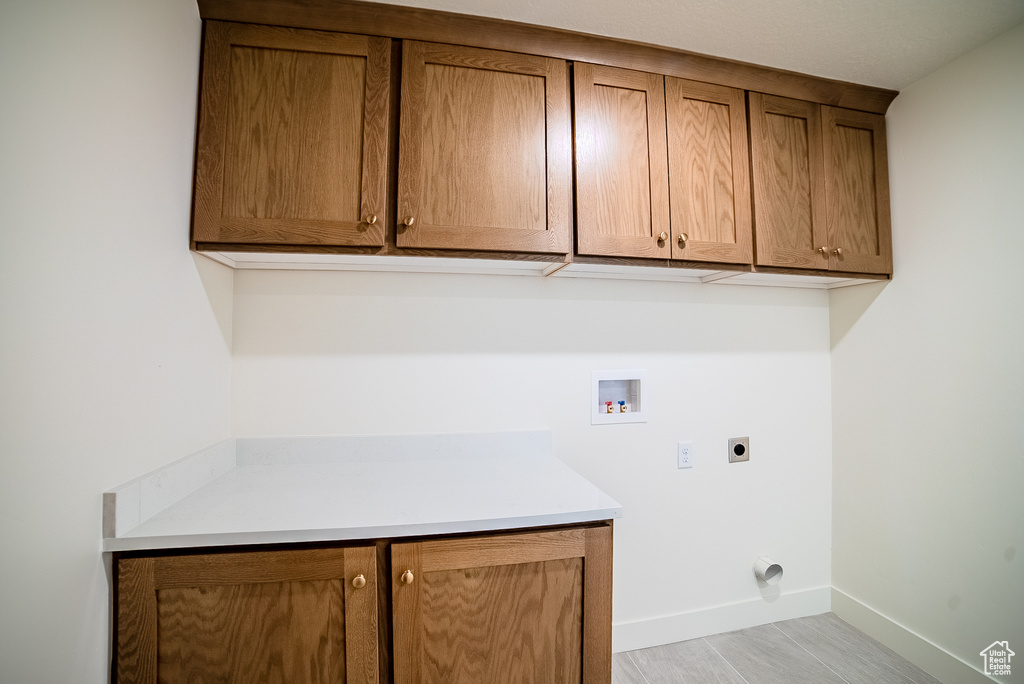 Laundry room with cabinet space, electric dryer hookup, hookup for a washing machine, and baseboards