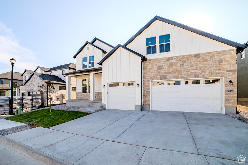 View of front of property with stone siding, board and batten siding, concrete driveway, and a garage