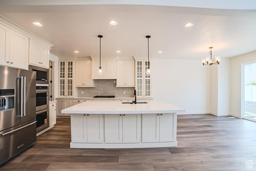 Kitchen with stainless steel appliances, light countertops, a chandelier, a sink, and recessed lighting