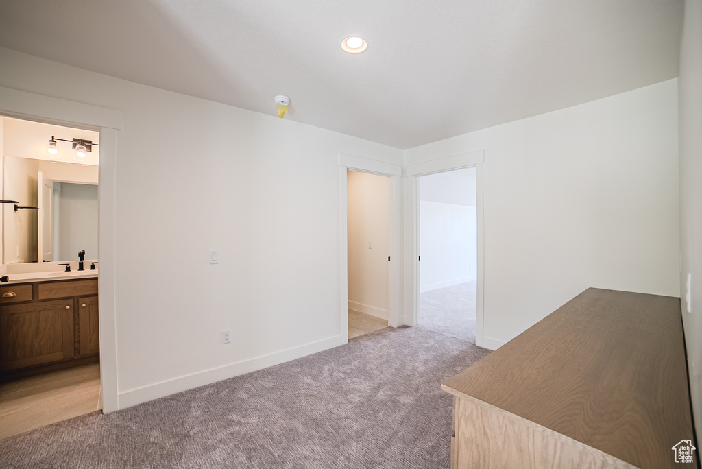 Unfurnished bedroom with light colored carpet, a sink, baseboards, ensuite bathroom, and recessed lighting