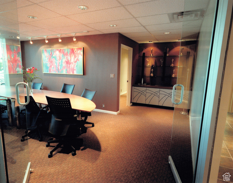 Office with carpet flooring, a paneled ceiling, baseboards, and rail lighting