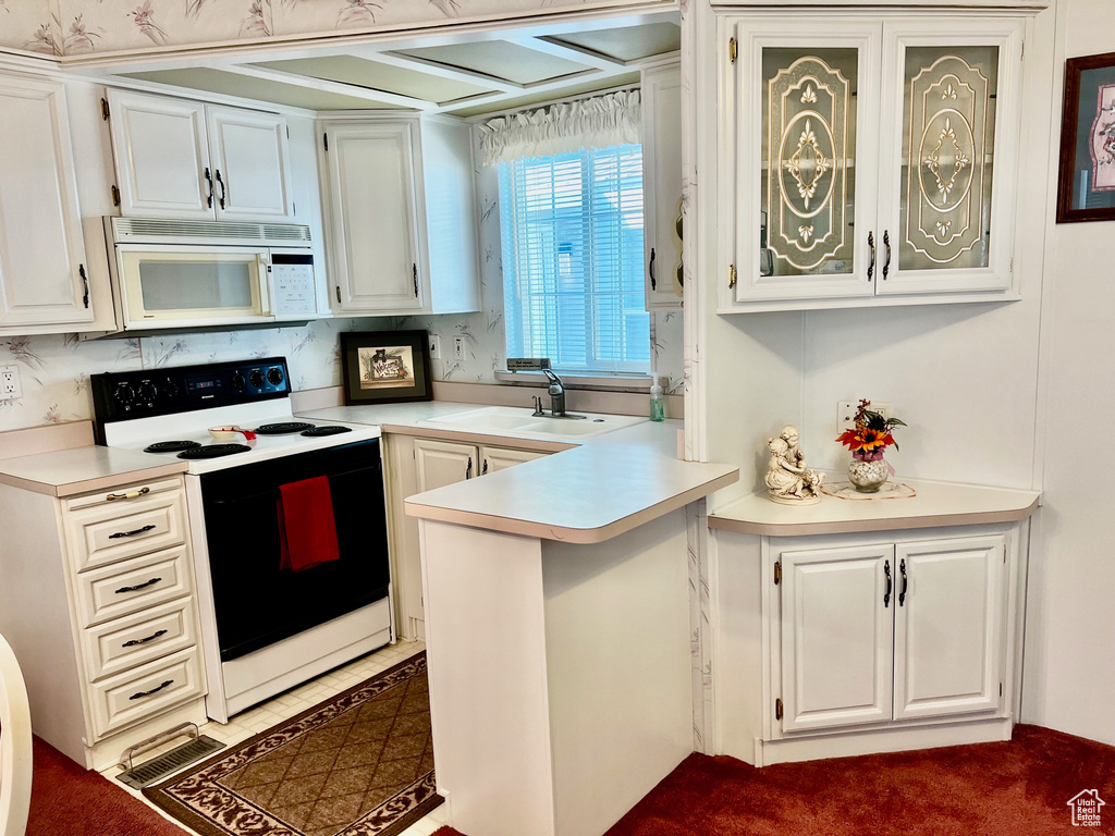 Kitchen with white microwave, range with electric stovetop, light countertops, glass insert cabinets, and white cabinets