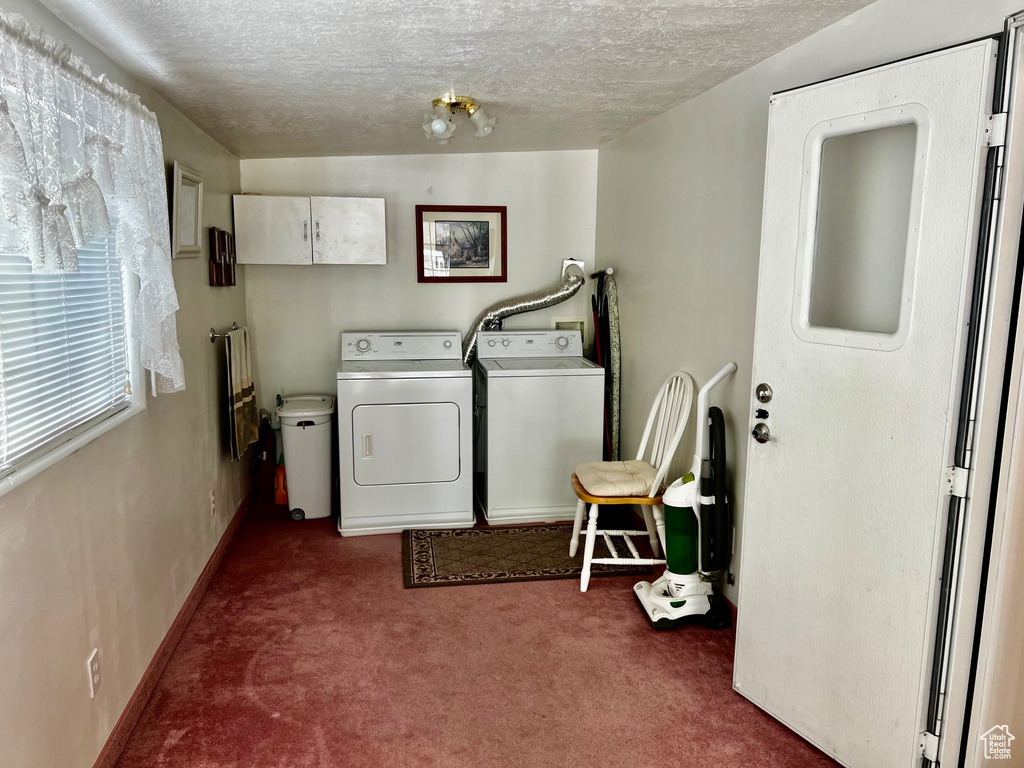Washroom featuring carpet, washer and clothes dryer, a textured ceiling, cabinet space, and baseboards