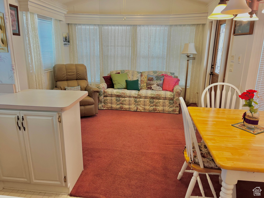Living area featuring light colored carpet, lofted ceiling, and crown molding