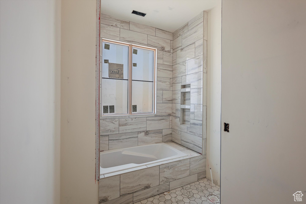 Full bath featuring tiled bath and tile patterned floors