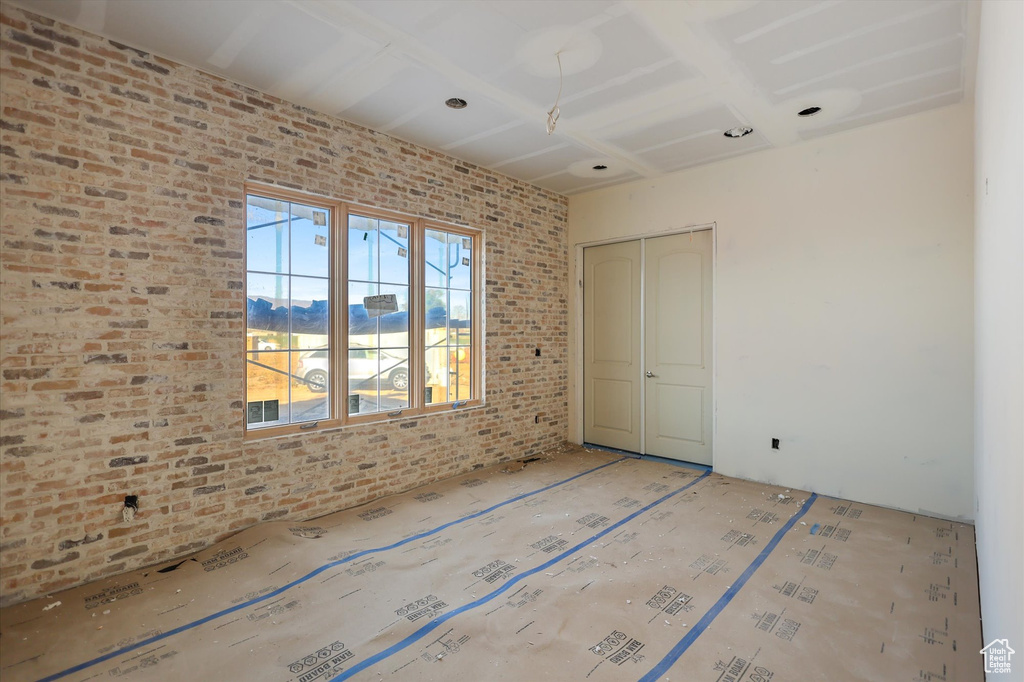 Unfurnished bedroom with brick wall and a closet