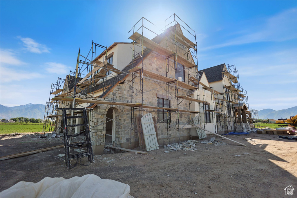 View of property exterior featuring stone siding, a mountain view, and stucco siding