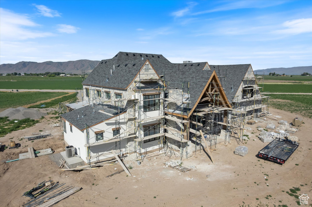 Rear view of property with a mountain view, central AC, a view of countryside, and roof with shingles