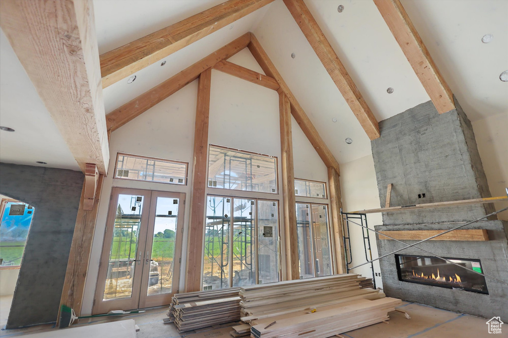 Living room featuring high vaulted ceiling, beamed ceiling, a fireplace, and french doors