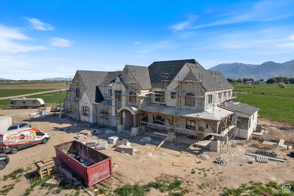 Rear view of property with stone siding, a view of countryside, a mountain view, and a shingled roof