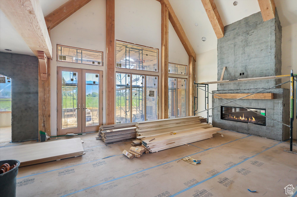 Living room with high vaulted ceiling, beamed ceiling, a large fireplace, and french doors