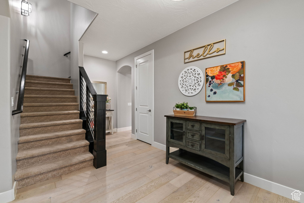 Stairway featuring arched walkways, wood finished floors, baseboards, and recessed lighting