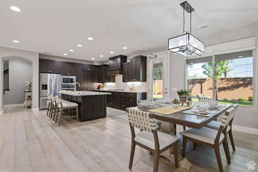 Dining area featuring arched walkways, baseboards, light wood-type flooring, a chandelier, and recessed lighting