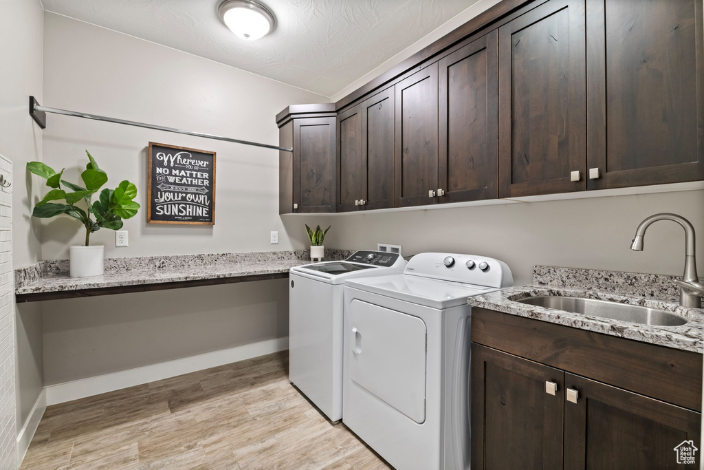 Laundry area with washer and dryer, cabinet space, light wood-type flooring, and baseboards
