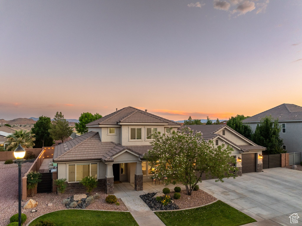 View of front of home featuring a tiled roof, stucco siding, concrete driveway, a garage, and stone siding