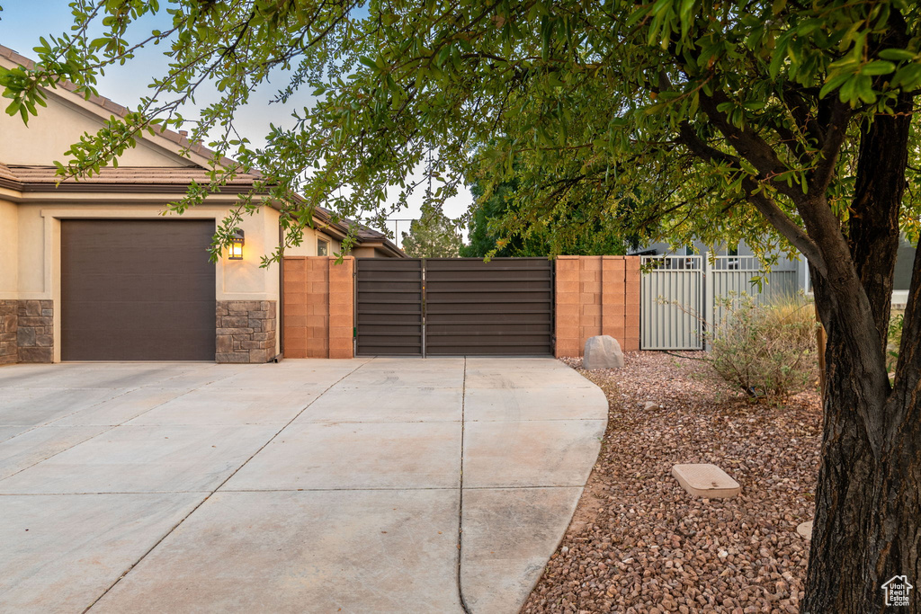 View of home's exterior with a gate, concrete driveway, stucco siding, and an attached garage